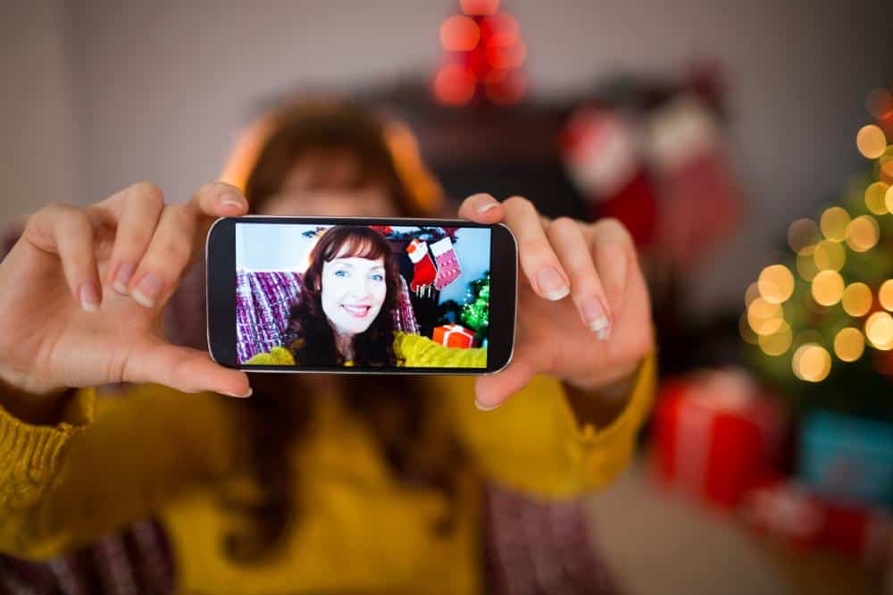 A redheaded woman taking a selfie with Christmas decorations