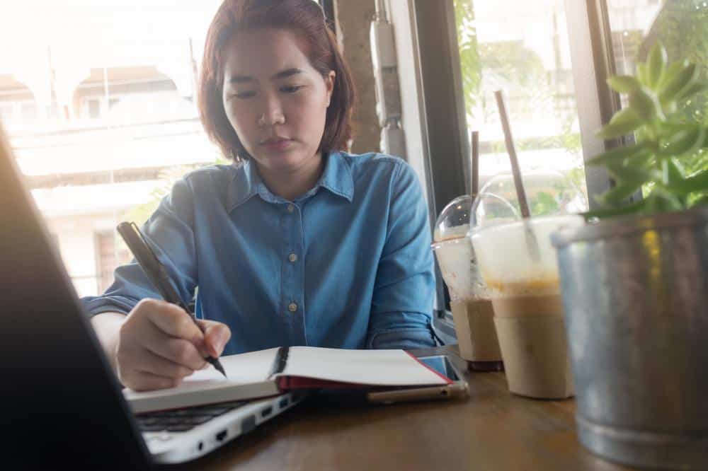 young Asian women writing in a journal